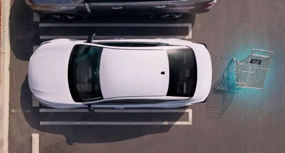 Top view of a white 2027 Nissan Altima in a parking lot with rear sensors detecting a shopping cart behind it at Hill Nissan in Winter Haven FL