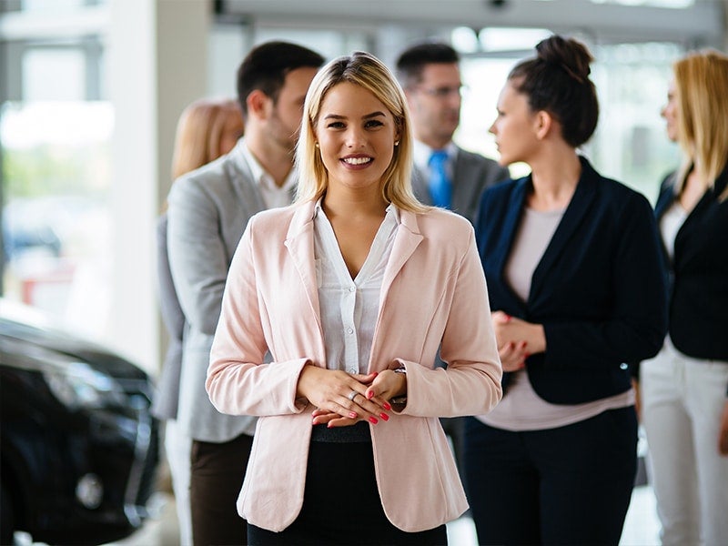women in office attire standing in front of colleague