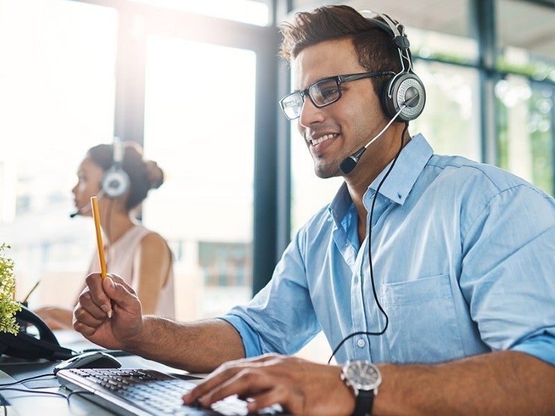Smiling man with headset working at computer in office