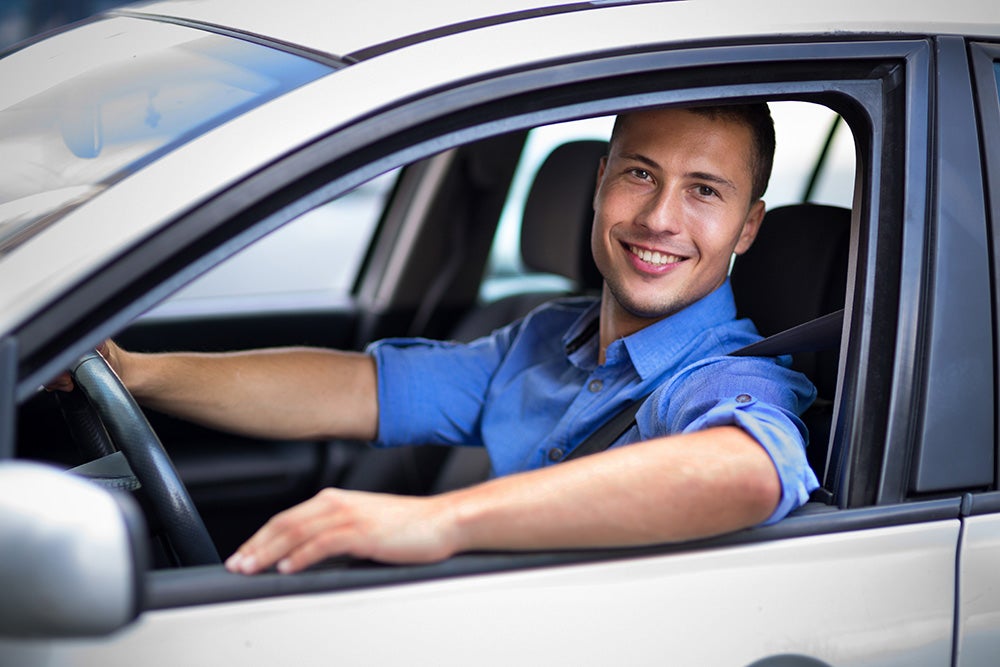man smiling while driving his car